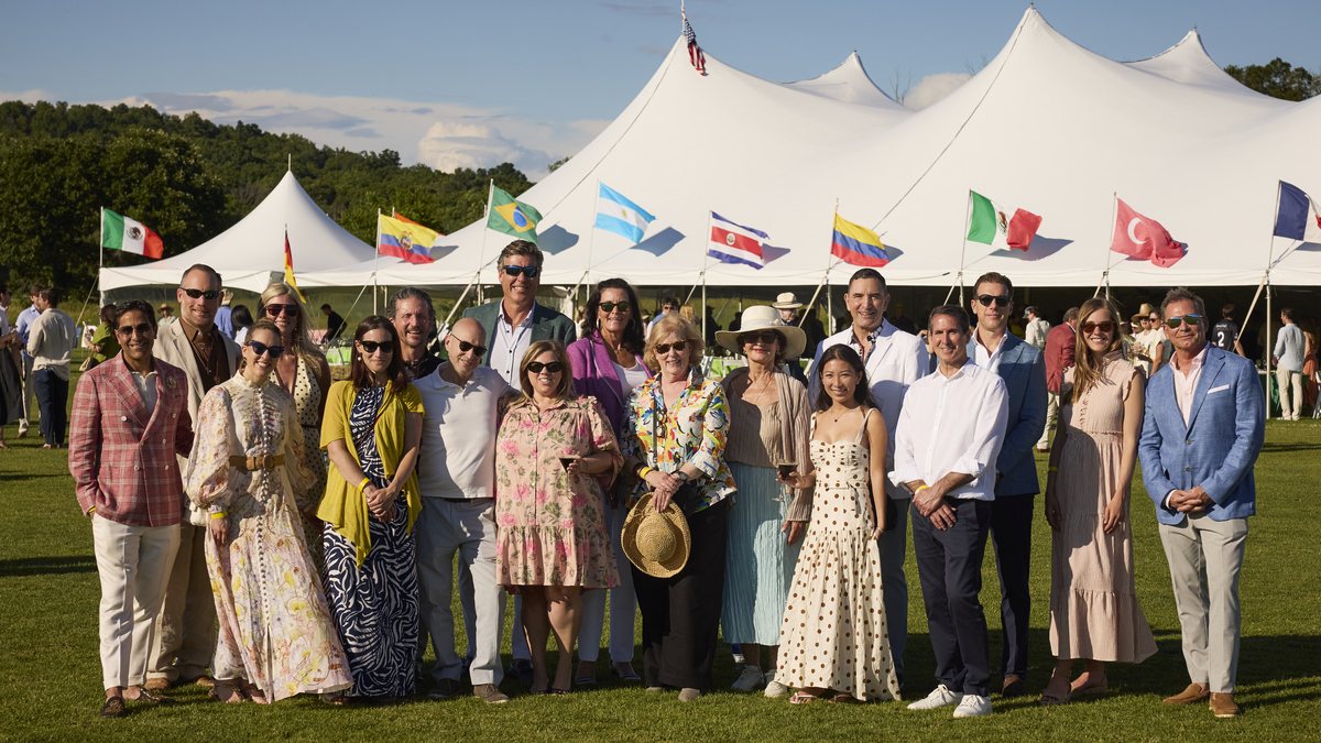 Guests gathered on the lawn in front of the polo tents